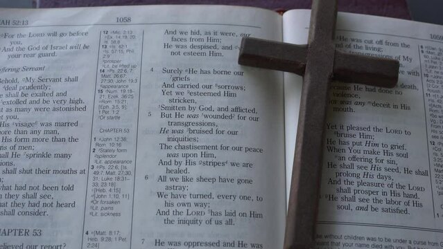 Bible scripture passage of the book of Isaiah 53 and verses 3-7. The suffering servant as Jesus of Nazareth. A wooden crucifix cross next to passage.