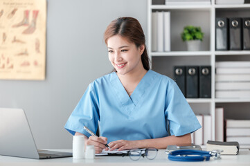 Asian female doctor working on laptop, filling out paperwork, patient medical history, reviewing documents at her workplace medical and health concept