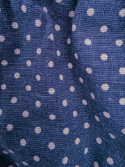 Wrinkled blue cotton fabric with white polka dots.