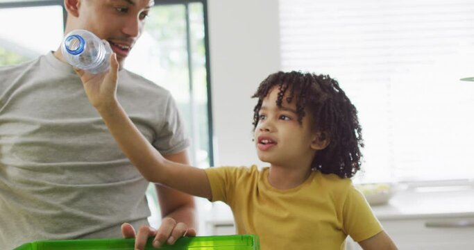 A young boy gives his father a high-five in the kitchen, with copy space