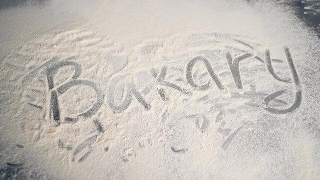 Creative inscription in large letter with flour on the kitchen surface on the table Bakery
