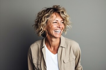 Portrait of a happy mature woman laughing against a grey background.