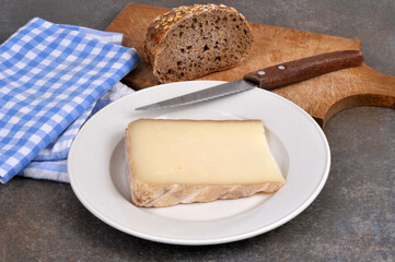 Morceau de tomme de brebis dans une assiette avec un couteau en gros plan.