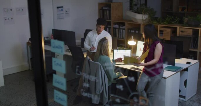 A diverse business team collaborates in a modern office working late