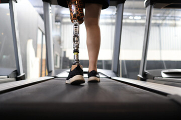 Athletic woman with a disability walking on a treadmill while exercising in a gym.