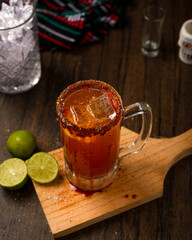 Michelada, typical mexican cocktail on a wooden table. Cocktail based on beer.