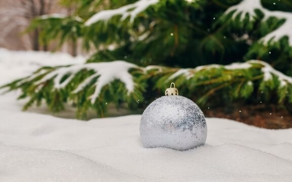 white ball with Christmas tree lies on pure snow. High quality photo