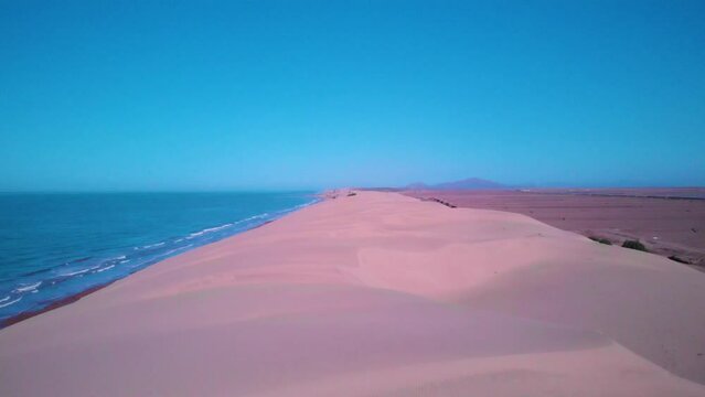 toma aerea con dron de Dunas  en medio del mar y el desierto en el hermoso estado de Sonora bajo un cuelo azul