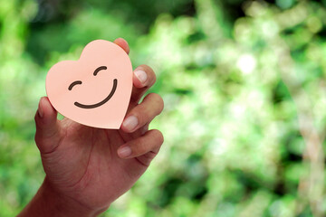 Hand holding happy smile face card. Concept of positive thinking, mental health, emotional...