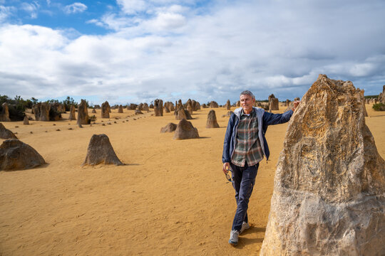 A happy man posing in front of sand and rocks in Pinnacles Desert