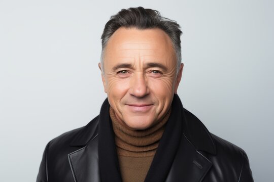 Portrait of mature man in black leather jacket and scarf on grey background