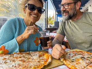 Meetings in a pizzeria. Beautiful smiling couple enjoying pizza, having fun together. Consumerism,...