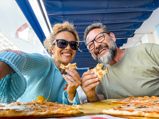 Smiling couple enjoy lunch at pizzeria. Beautiful smiling couple taking selfie and having fun in...