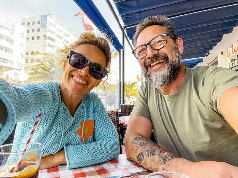 Smiling couple enjoying time at the restaurant drinking and talking in the open air dehor having fun together. Consumerism, food, lifestyle concept