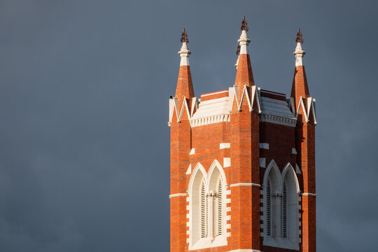 Close up view of a tall historic church steeple against a dark sky