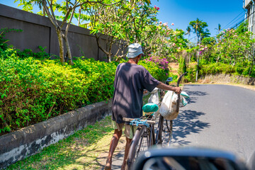 Bali, Indonesia - August 29, 2023: Man with bicycle along the major road