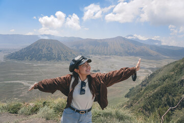 An Asian girl standing on a hill track in Bromo, enjoying view of Bromo, a wonderful scenery in...