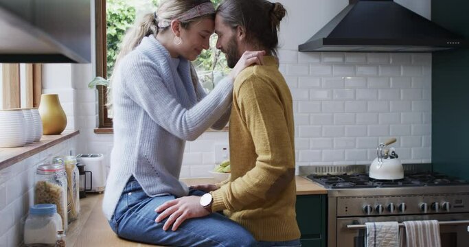 Caucasian couple shares a tender moment in the kitchen, hugging