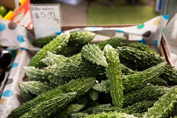 a tray of bitter melon for sale at a farmers market