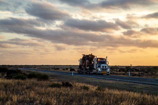Semi trailer truck driving at dusk on Eyre Highway along the Nullarbor Plain