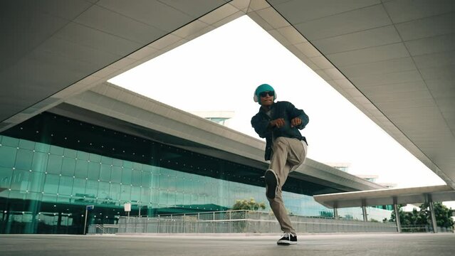 Happy hipster practice b boy dance with stylish cloth at building. Skilled street dancer enjoy show footstep performance. Modern lifestyle, break dancing. Slow motion. Outdoor sport 2024. Sprightly.