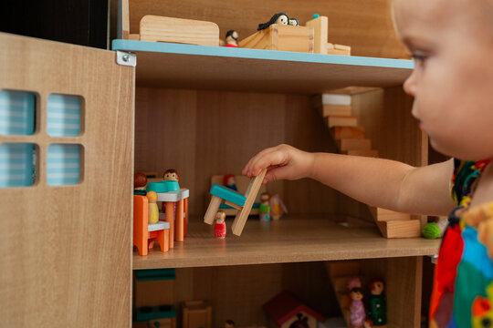 Toddler playing with wooden dolls house in morning    