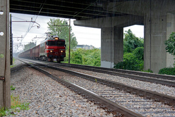 A traditional electric railway locomotive comes under the bridge