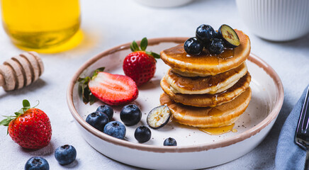 Pancakes on a plate with berries and honey