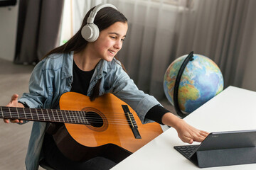 Portrait of smiling teen student practicing guitar during music lessons 