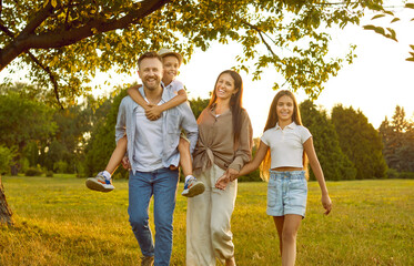 Happy family spending time in green park. Cheerful smiling mother, father and children enjoying...