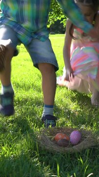 Two children boy and girl having easter egg hunt in garden backyard