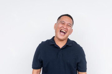 Obraz premium Portrait of a cheerful middle-aged Asian man laughing heartily, isolated on a clean white background, depicting happiness.