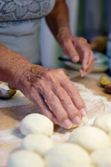 Preparation of homemade fruit dumplings with plums. Czech specialty of sweet good food. Dough on kitchen wooden table with hands.