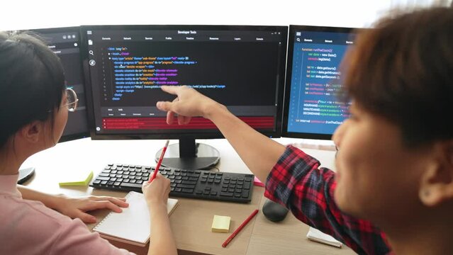 Slow motion back end software developer engineer for computer programming working together on debugging writing computing code, solving complex algorithms display on monitor in office. Burgeoning