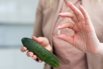 Female hand holding a large fresh cucumber on white background.
