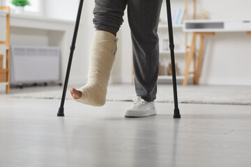 Person with a broken leg walking with crutches at home. Cropped shot of an unrecognizable African...