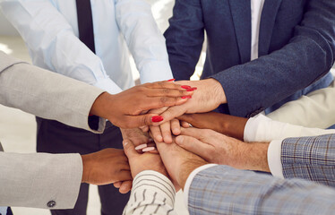 Close up top view photo of diverse business people putting their arms together. Stack of hands of a...