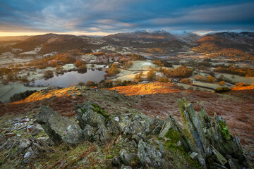 Wide angle view of Loughrigg Tarn at sunrise with golden light on a frosty landscape. Lake District, UK. - 738611035