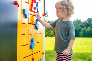 Little boy explores outdoor rebus on playground - obrazy, fototapety, plakaty
