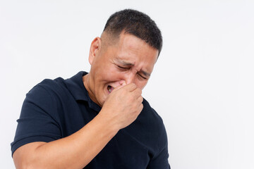 Middle-aged Asian man grimacing and holding his nose, reacting to a foul smell, isolated on a white background.