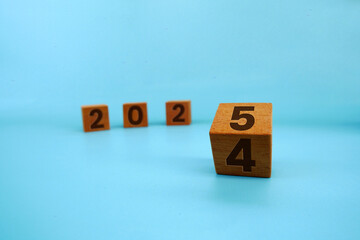 Wooden cube with letters 2025 on it isolated on blue background.. Concept of new year 2025