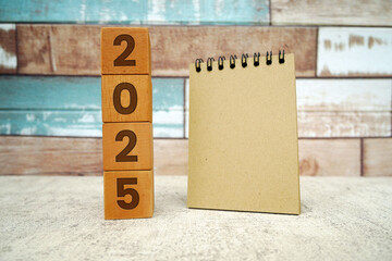 Wooden block with engraved year 2025 and spiral notepad. Happy new year 2025.