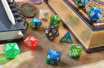 Dice for playing dnd, rpg, fantasy games. twenty-sided cube and polyhedral cubes .Close up of spilling out dice of different kinds , book, pencil..