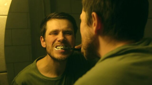 millennial person before bed. Brushing teeth man looking in mirror of home bathroom sink toothbrush morning routine for clean dental oral care. Back view from behind male reflection in evening night