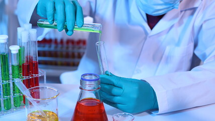 Scientists are doing research in a science lab. A medical chemist in a white coat, gloves and...