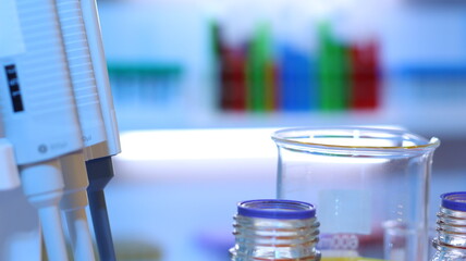 Scientists are doing research in a science lab. A medical chemist in a white coat, gloves and goggles looks at a glass tube. Compare two different liquid samples. and discuss future experiments.
