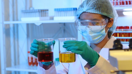 Scientists are doing research in a science lab. A medical chemist in a white coat, gloves and...