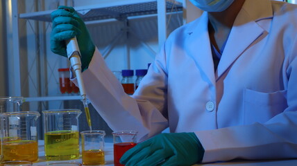 Scientists are doing research in a science lab. A medical chemist in a white coat, gloves and...