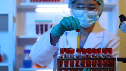 Scientists are doing research in a science lab. A medical chemist in a white coat, gloves and...