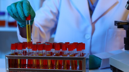 Scientists are doing research in a science lab. A medical chemist in a white coat, gloves and...